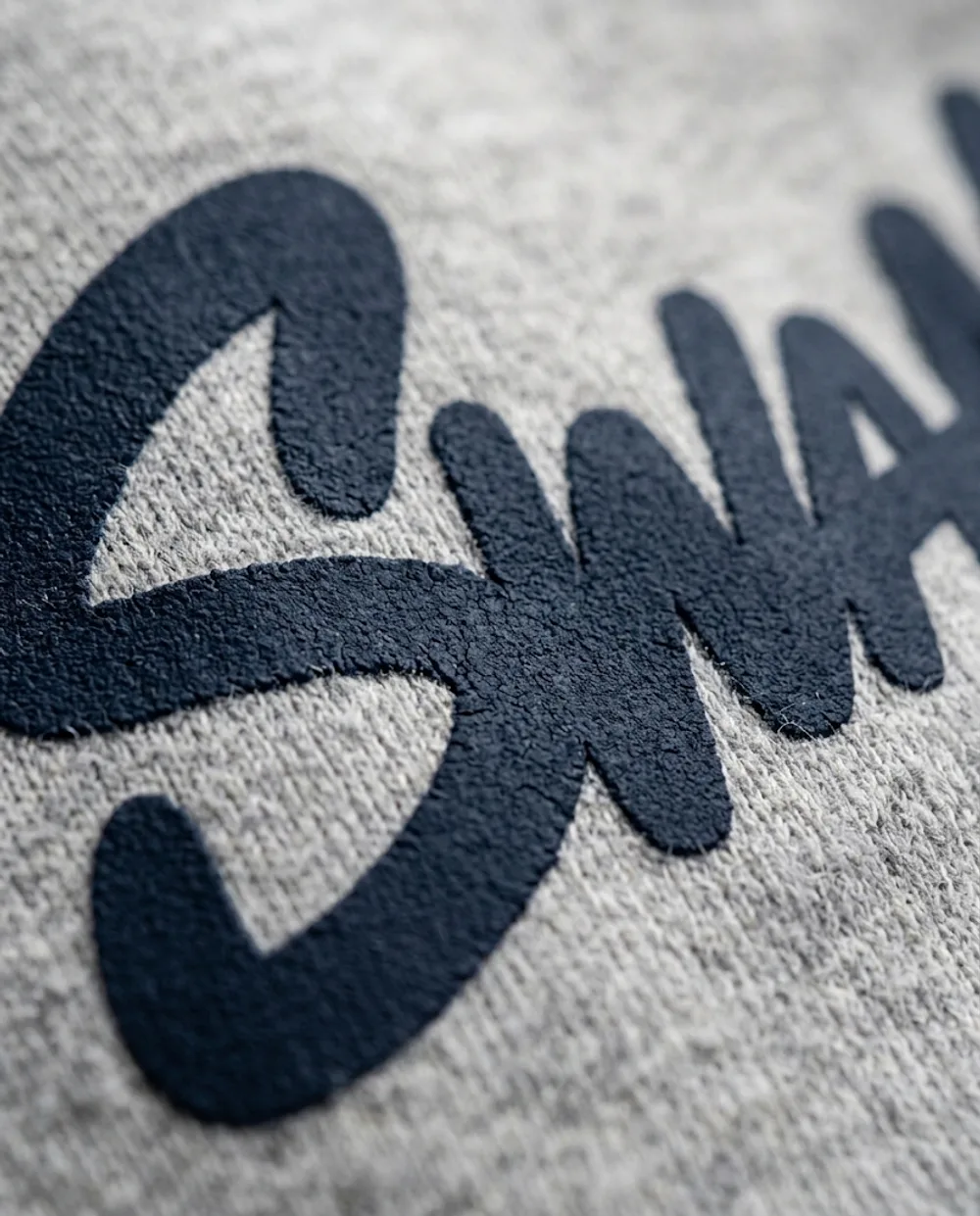 Close-up of the raised navy SWANK print on heather grey fleece